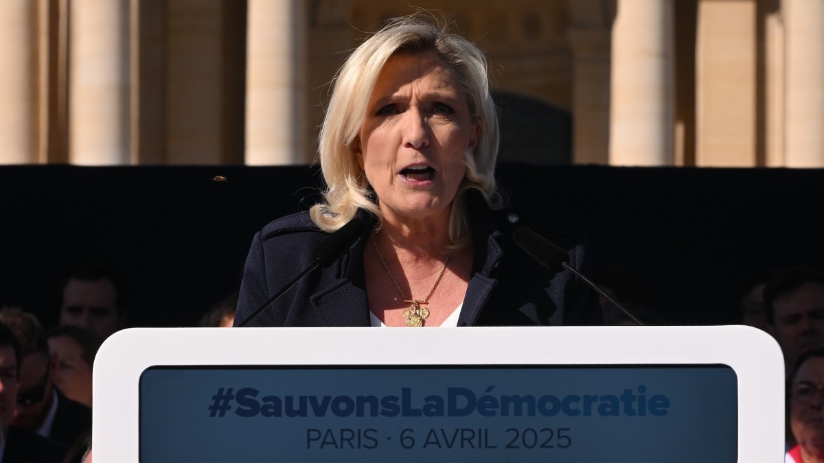 Marine Le Pen speaks during a demonstration in her support after her conviction above a banner reading 'Let's save democracy '.