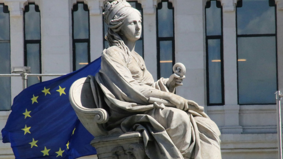 Estatua de la diosa Cibeles en Madrid con la bandera de la Unión Europea al fondo.