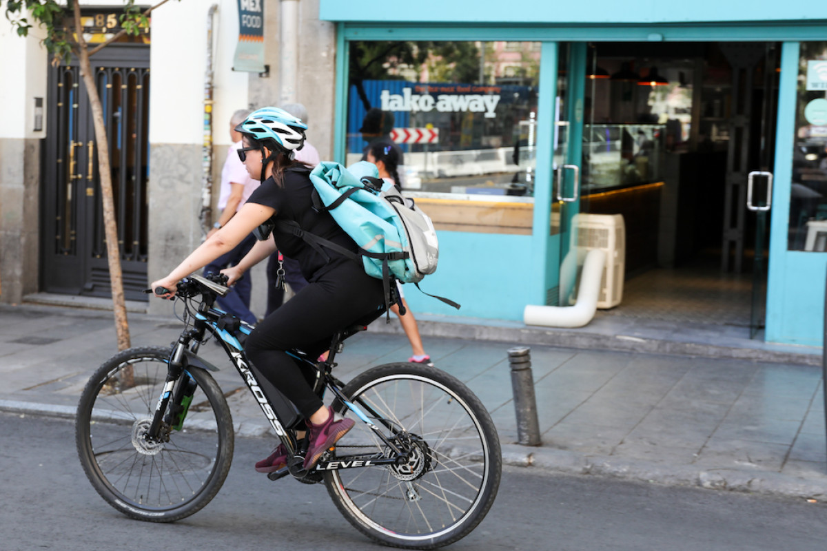 Fotografía de una repartidora transitando en bicicleta por una calle del centro de Madrid.