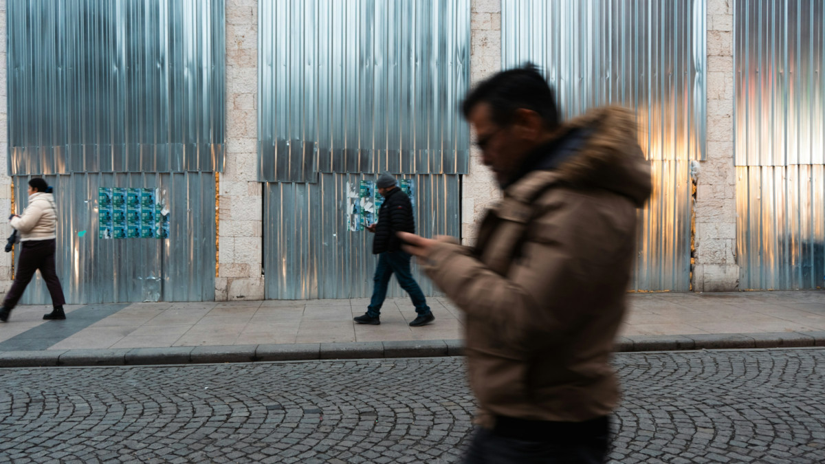 Dos personas caminan por la calle atentas a sus móviles.