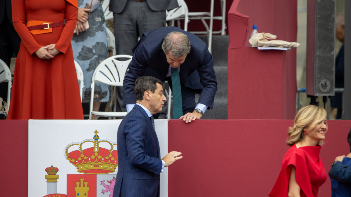 El presidente del PP, Alberto Núñez Feijóo, saluda desde una grada al presidente de la Junta de Andalucía, Juanma Moreno Bonilla.