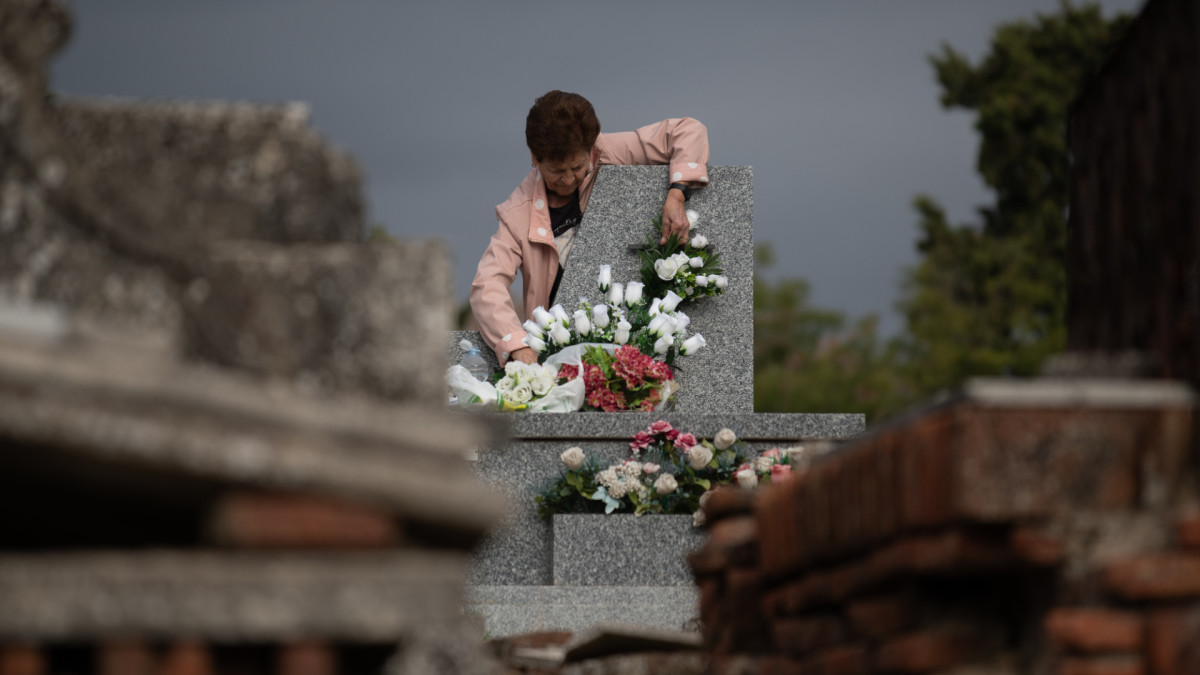 Una persona deja un ramo de flores en una tumba en el día de Todos los Santos.