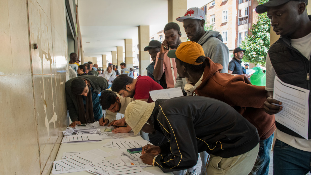 Varias personas hacen cola para la tramitación de su regularización administrativa