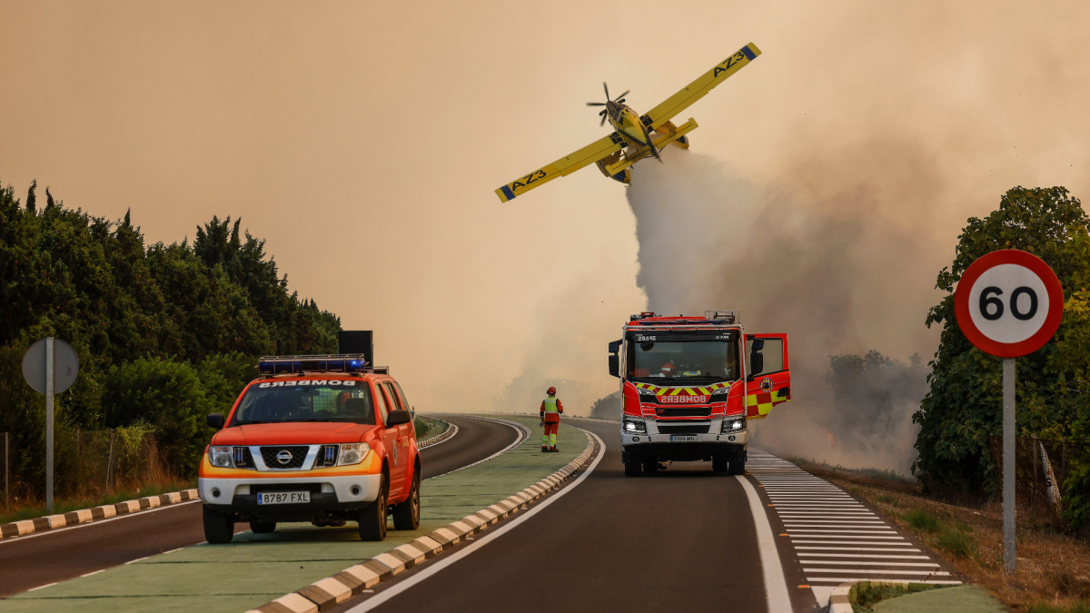 Un avión y coches de bomberos durante las labores de extinción de un incendio forestal (València).