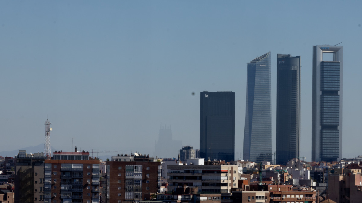 En primer plano, una serie de edificios de un barrio residencial y, de fondo, el espacio financiero de 'las cuatro torres' en Madrid. | Eduardo Parra / Europa Press