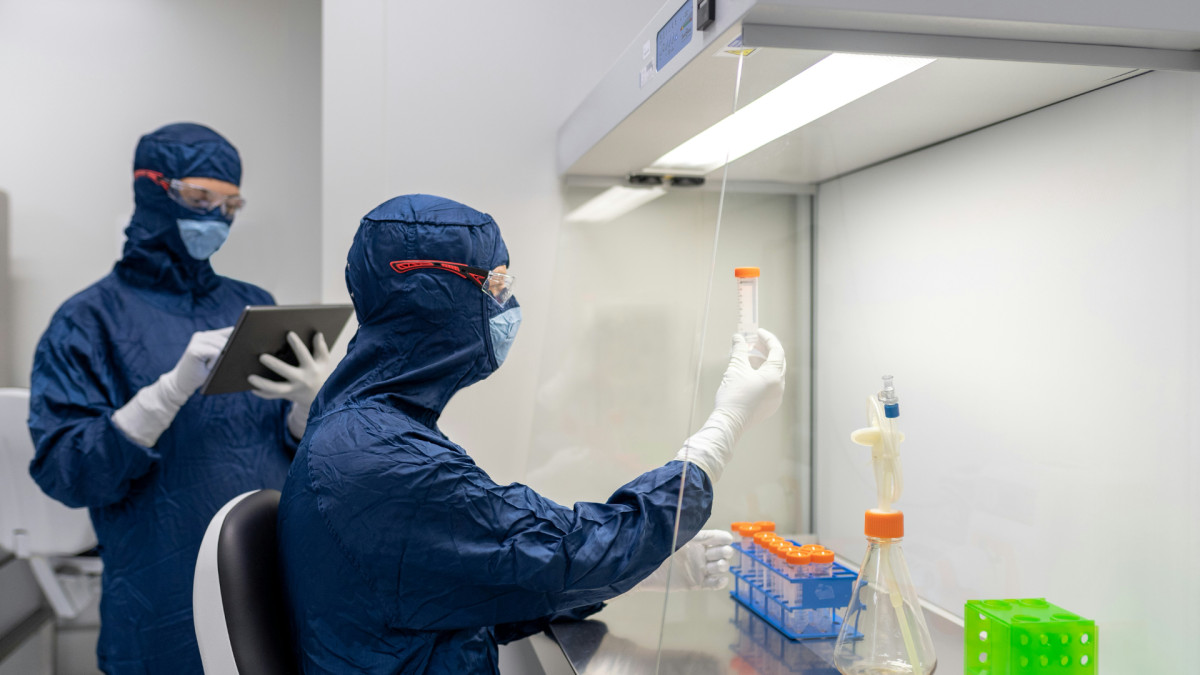 Personal científico con trajes de protección trabajando en instalaciones industriales farmacéuticas | Unsplash / Shanjir H